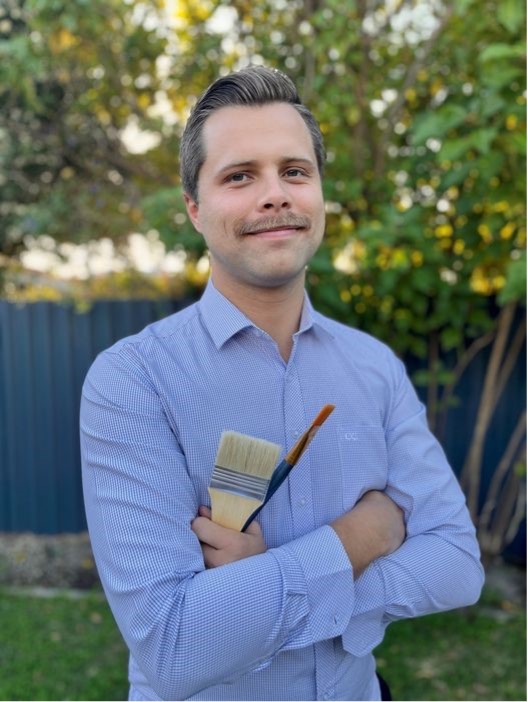 Man holding paint brushes.