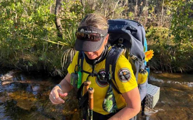 Woman in hiking gear crossing creek