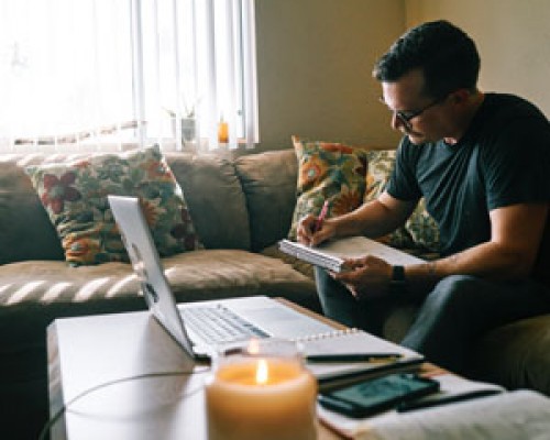 man working on computer with notebook